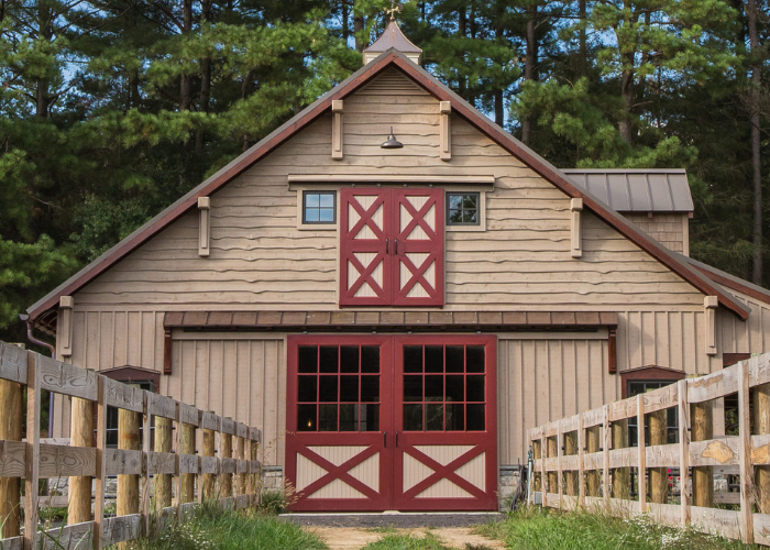 Front exterior of brown and red barn with red double doors and red loft doors.